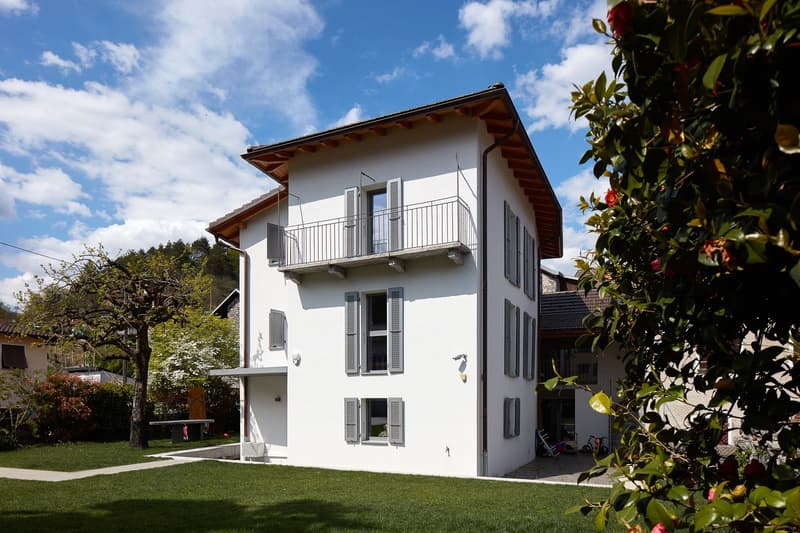 2 story house, white exterior, brown roof, balcony, large windows, garden, lawn
