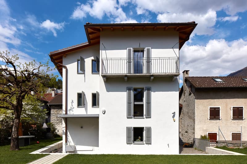 modern white house, brown roof, balcony, windows with shutters, garden, lawn
