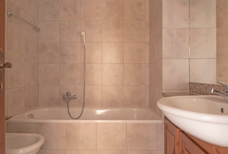 Tiled bathroom with a bathtub, shower, and sink