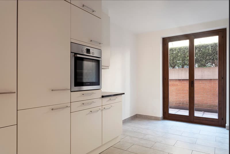 modern kitchen with white cabinets, stainless steel oven, wooden sliding door to balcony