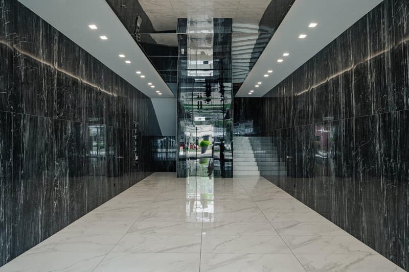 White marble floor, black marble walls, glass staircase with metal handrail, recessed lighting, empty space