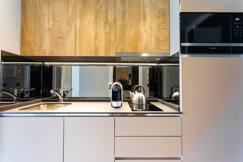 Modern kitchen with wooden cabinets, stainless steel appliances including a microwave and coffee maker, and a sink with faucet.
