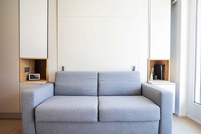 Gray sofa, built-in shelves on either side, large window providing natural light