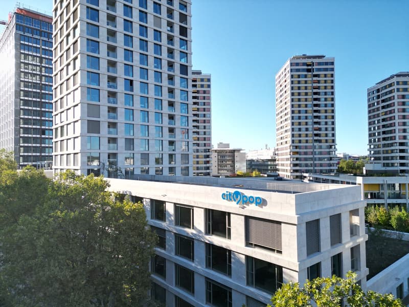 Multi-story commercial building with glass windows, the building has the 'Citypop' logo on the facade, surrounded by other high-rise buildings and trees