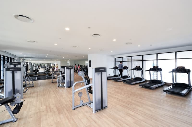 Large, well-equipped gym with various fitness equipment such as treadmills, weight machines, and other exercise machines. The gym has a spacious and bright interior with hardwood floors and large windows.