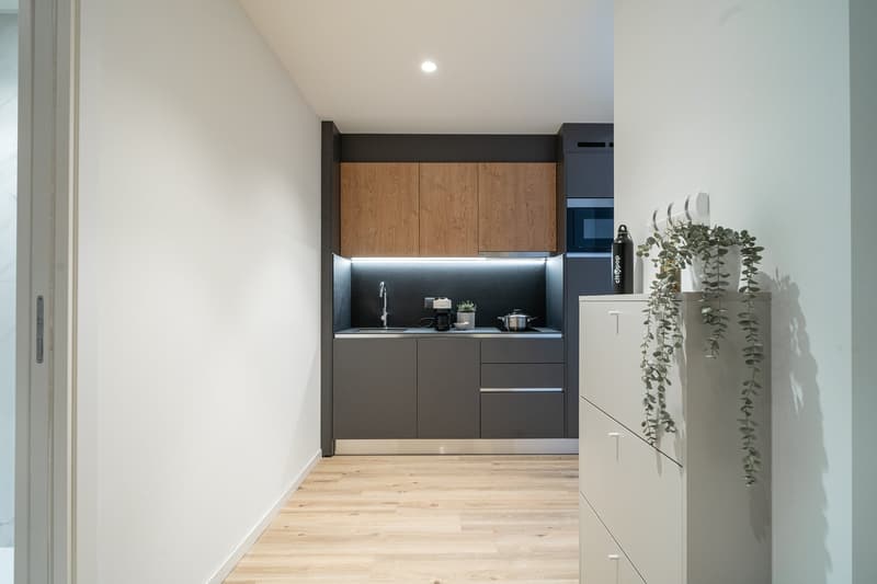 Modern kitchen with gray cabinets, wooden upper cabinets, hardwood flooring, and a dishwasher visible