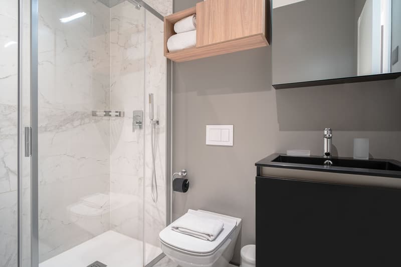 Bathroom: walk-in shower, sink, cabinet, toilet, white tiles, towels, towel rack, mirror