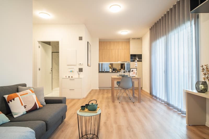 living room, hardwood floor, couch, coffee table, dining table with chairs, kitchen, windows, microwave, tea set, curtains