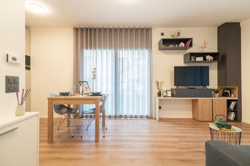 Dining table, chairs, television, wooden floors, white curtain