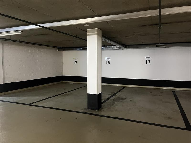 Empty underground parking space with parking spots numbered 17, 18, and 19, and a central white column.