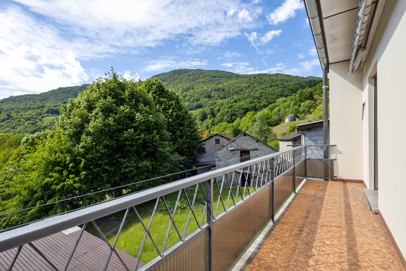 / Dai due balconi che si affacciano verso ovest, la vista si estende attraverso il verde fino al Monte Tamaro.