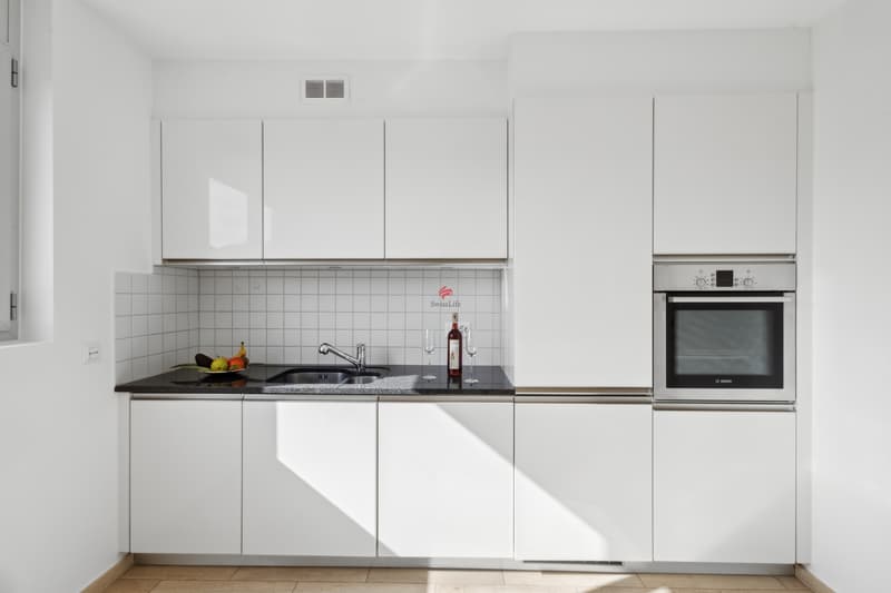 Die moderne, geradlinige Küche ist mit weiss lackierten Möbeln und Unterschrankbeleuchtung ausgestattet und eignet sich perfekt für alle, die gerne kochen / La cucina, moderna e lineare, è dotata
