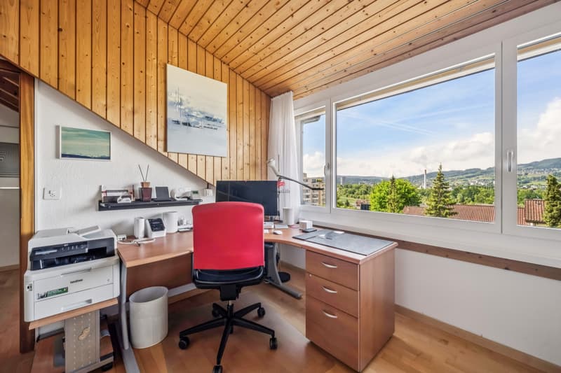 Heimbüro mit beeindruckender Weitsicht. / a home office with a red chair, desk, and large window