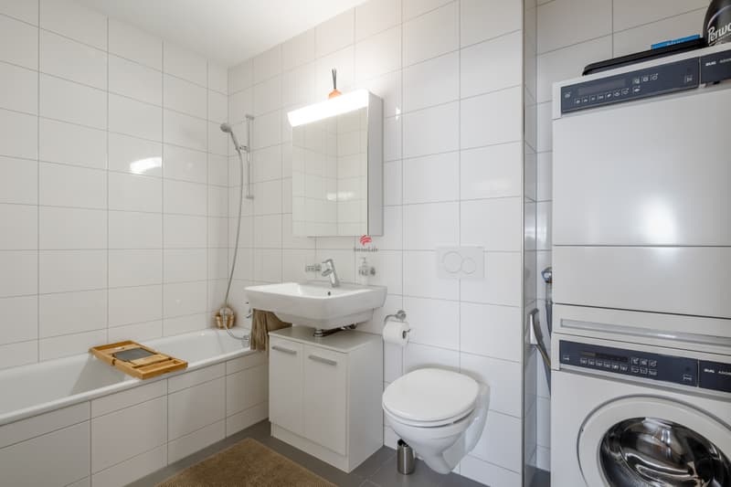 Badezimmer mit Badewanne und Waschturm, klar und funktional gestaltet