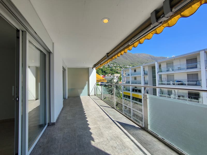 Raffinierte überdachte Terrasse mit dunklem Plattenboden und Blick in die Ferne, ideal für entspannende Momente an der frischen Luft / Terrazza coperta raffinata con pavimento in lastre scure e vist