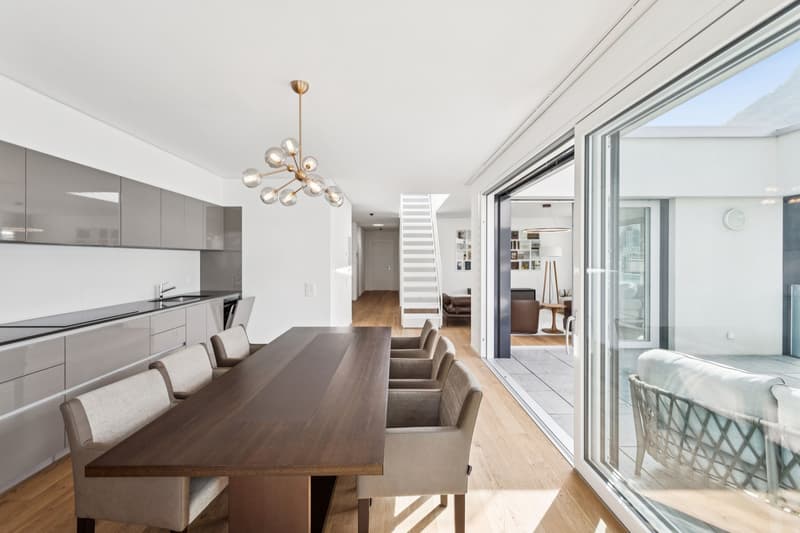 Dining room with a large wooden table, modern chandelier, and large windows
