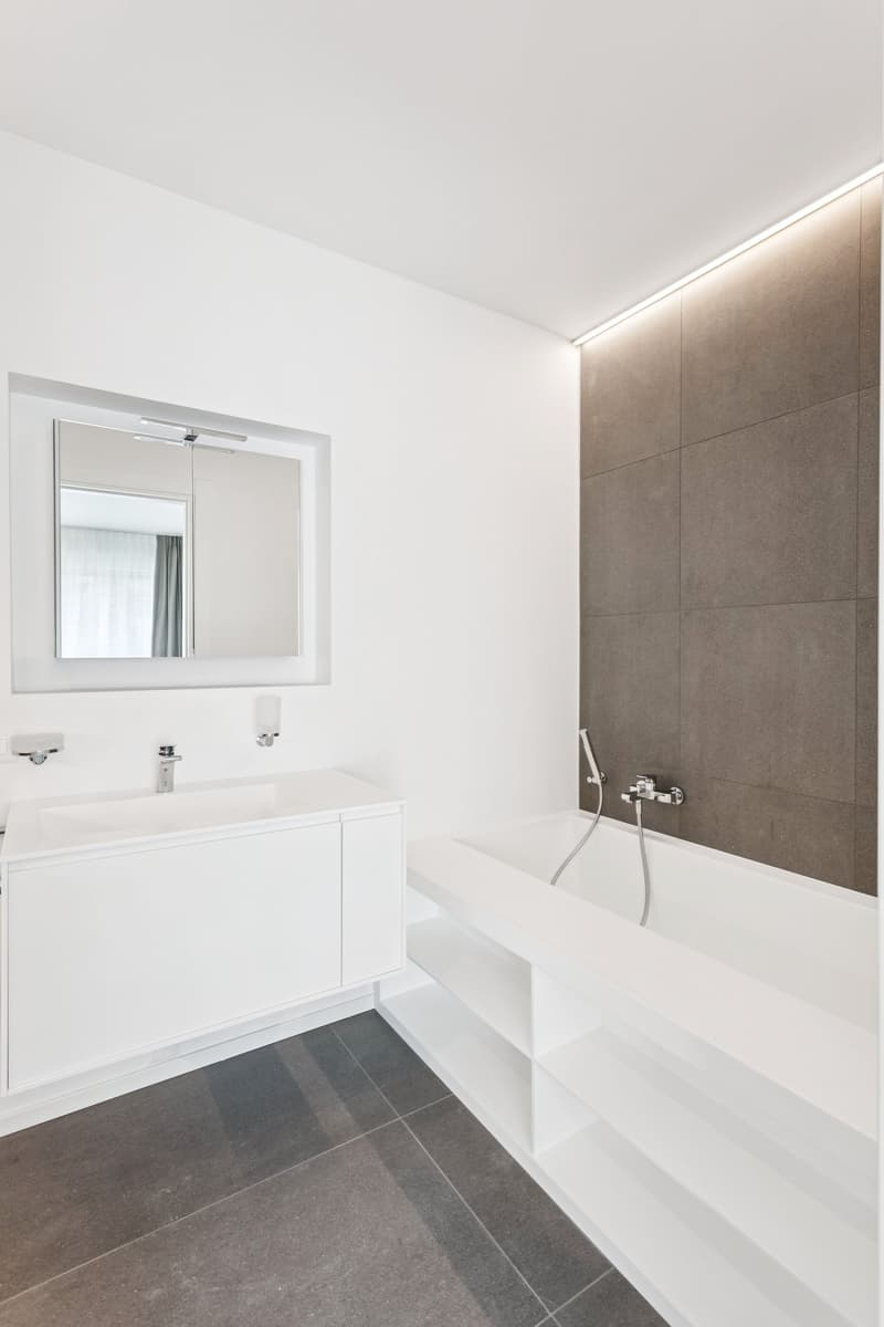 modern bathroom, white tiles, white vanity, mirror, bathtub, shower, faucets, shelves