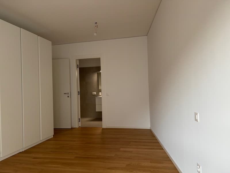 empty room, wooden floor, white walls, modern lighting, double wardrobe, open door leading to bathroom