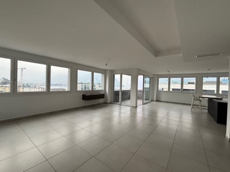 Empty living room with tiled floor, glass doors, windows and a view of the city