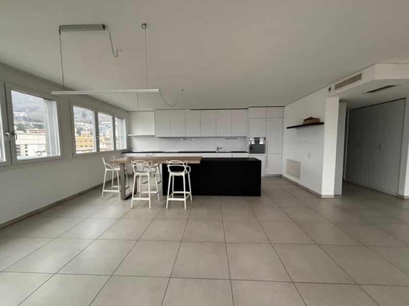Open floor plan, modern kitchen with large dining table, white cabinets, granite countertop, large windows, modern lighting fixtures, tiled floor