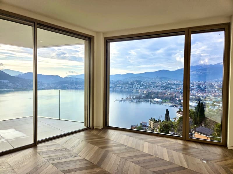 expansive living area with floor-to-ceiling windows leading to balcony, wooden herringbone flooring, stunning lake and city views