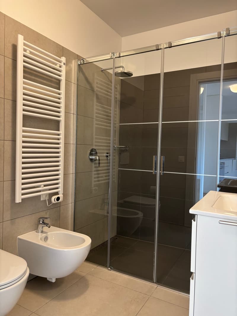 modern bathroom with glass shower, white toilet, white sink, white wall, white floor