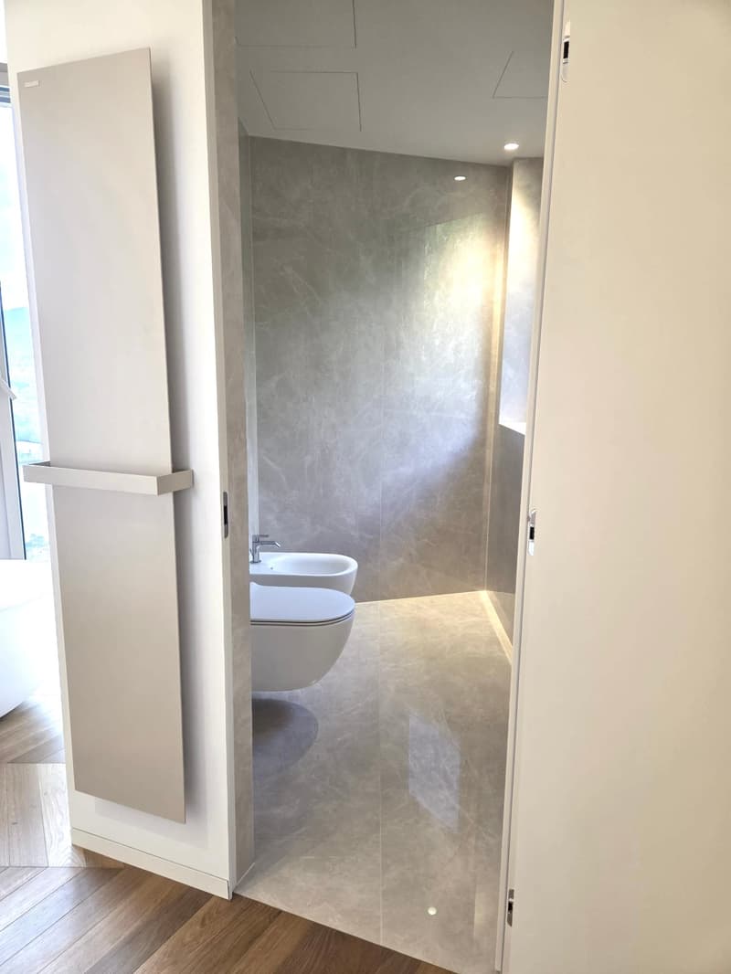 Modern bathroom with white fixtures, gray walls, wooden floor