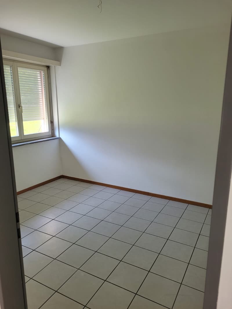 Empty room with white walls, tile flooring, and a window.