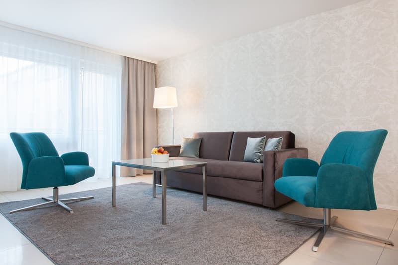 Two armchairs, coffee table, sofa, carpet, bowl of fruit, floor lamp, large window, beige curtain, wall.