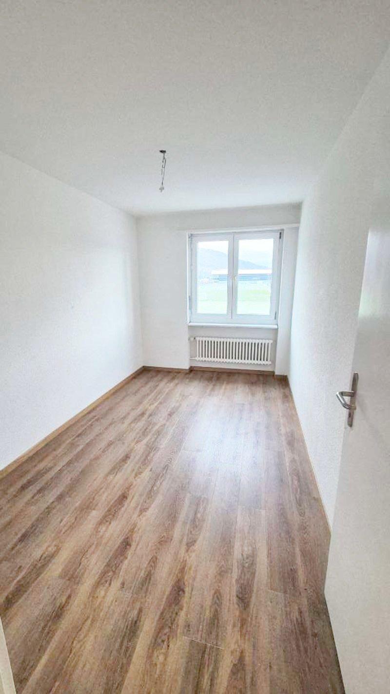 empty room with white walls, wooden floor, window with white frame, door