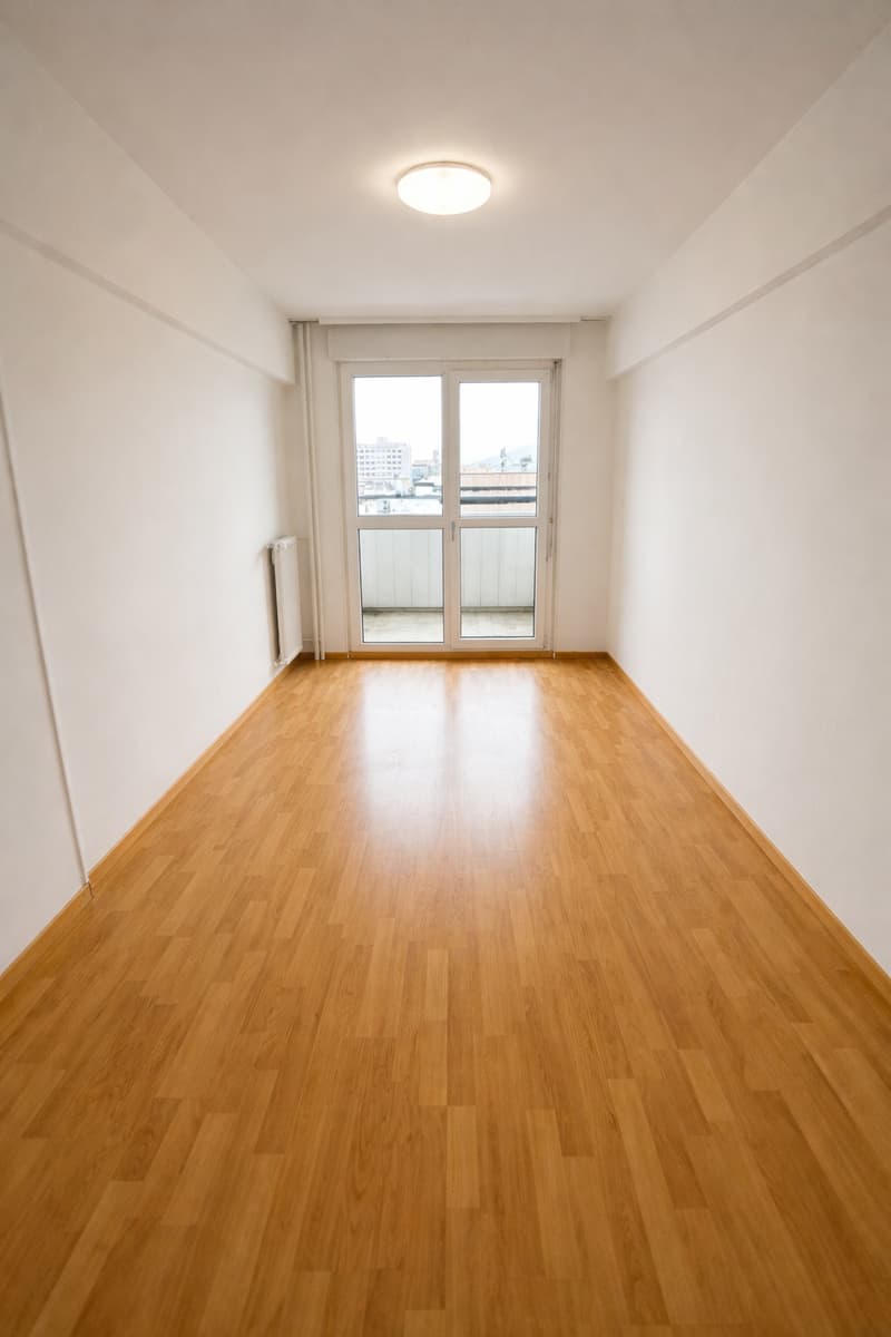 empty room, wooden floors, glass doors leading to balcony, white walls, built-in heater