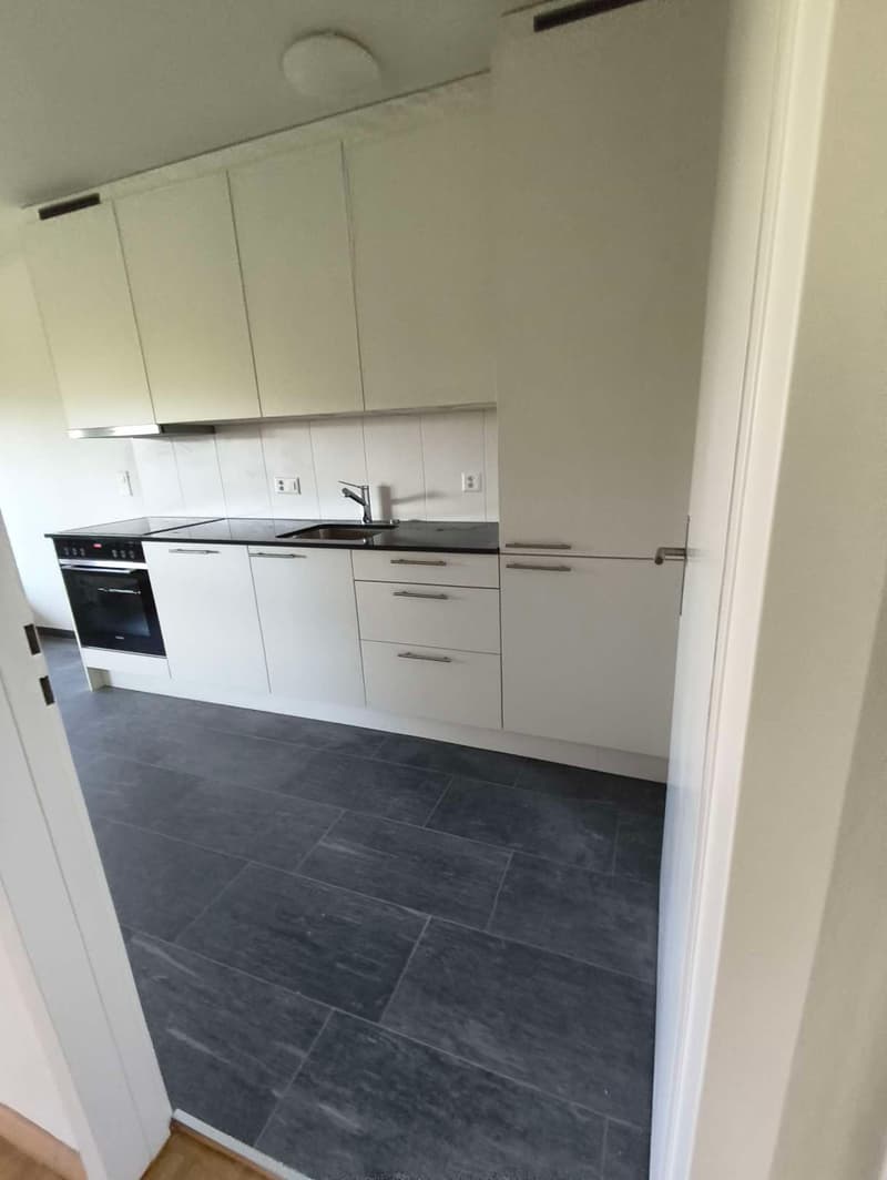 modern kitchen with white cabinets, black countertops, integrated oven, sink, faucet, dishwasher, washing machine