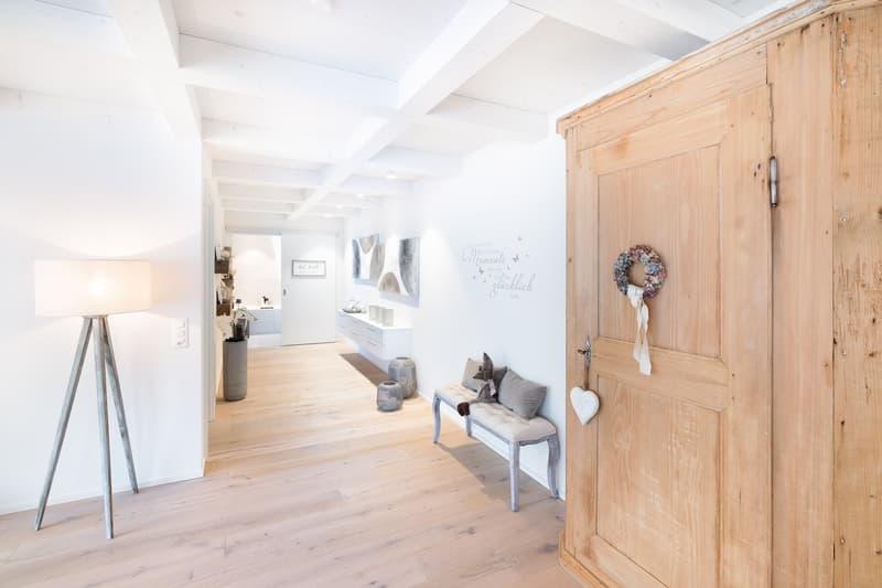 wooden floor, white walls, wooden door, bench, lamp, flower vase, wall art