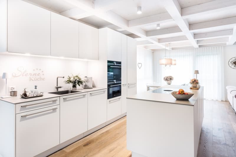 modern kitchen, white cabinets, wooden floor, island with sink, oven, dishwasher, refrigerator, countertop with fruit bowl