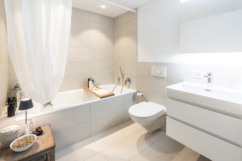 Bathroom with bathtub, toilet, sink, and white tiles
