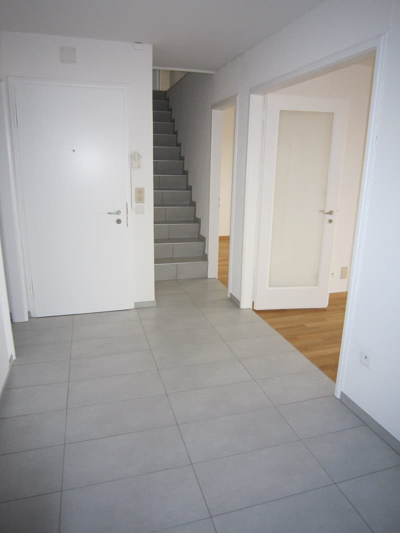 Empty room, white walls, gray tiles, white doors, staircase