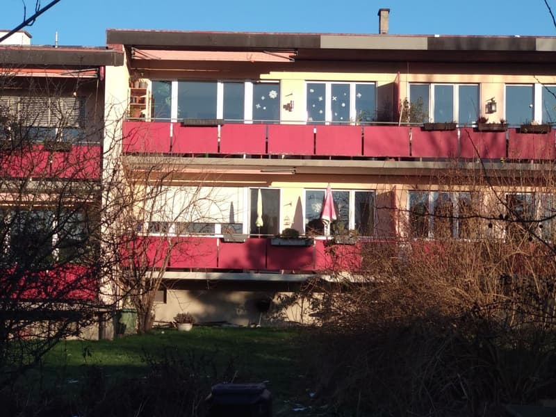 3 story building, red and yellow facade, multiple balconies