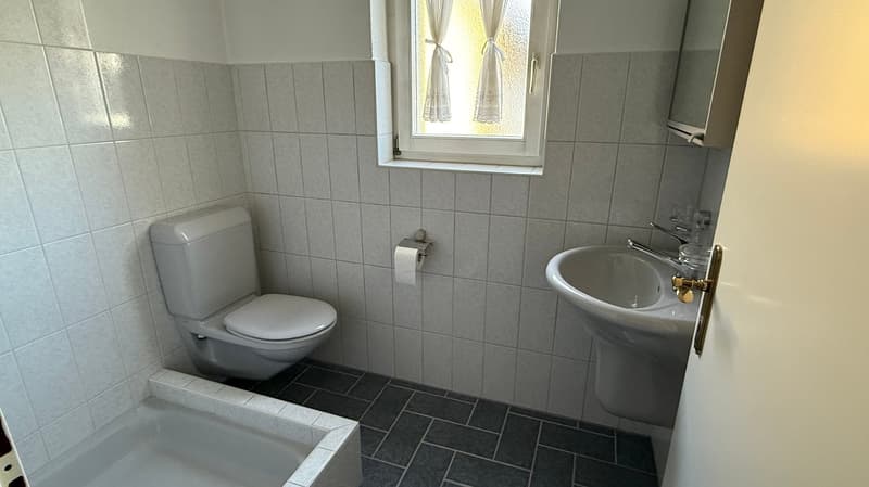 Bathroom: Toilet, bathtub, sink, tile walls, window