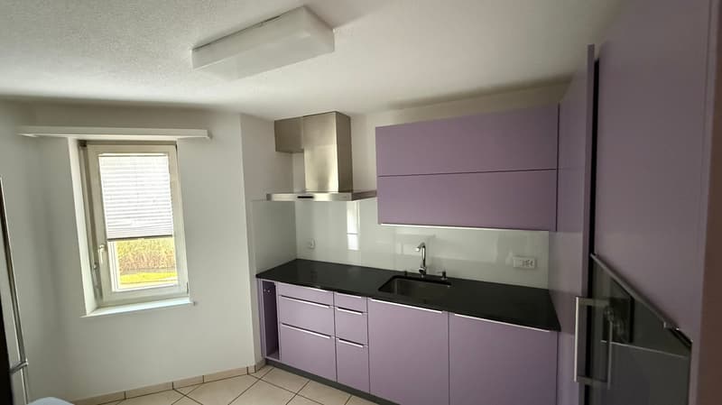 modern kitchen, white cabinets, black countertops, stainless steel exhaust hood, sink with faucet, window with blinds, tiled floor