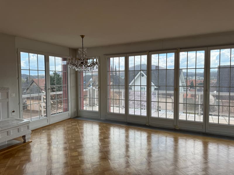 large room, wooden floor, chandelier, sliding glass doors, balcony, view of the city