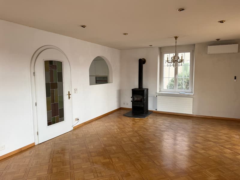 empty room, wooden floor, white walls, fireplace, chandelier, window, radiator