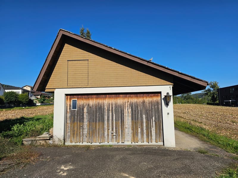Single garage building, wooden door, brick and stone wall, lamp on the side