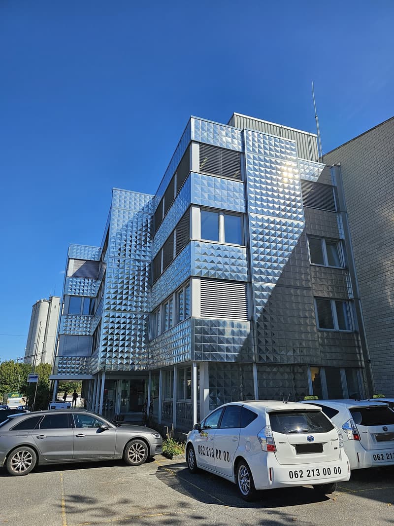 modern building, multiple floors, glass and metal facade, parking lot in front
