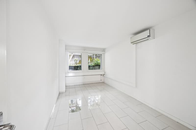 Empty room with white walls, white tiled floor, two windows, air conditioner mounted on the wall