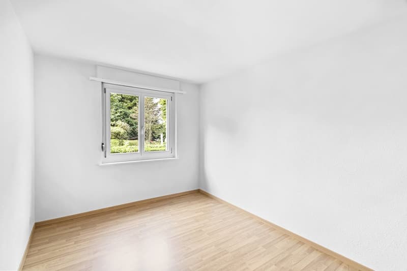 empty room, white walls, wooden floor, window with view of trees