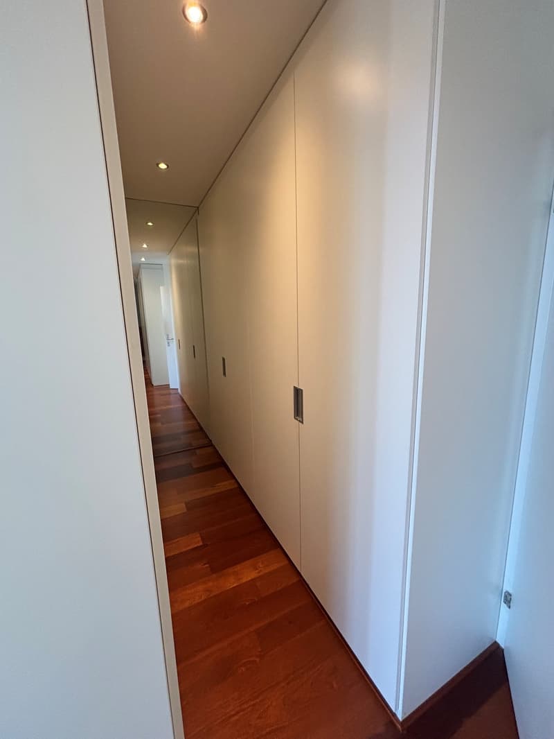 wide hallway, white walls, wooden floor, high ceiling, lights