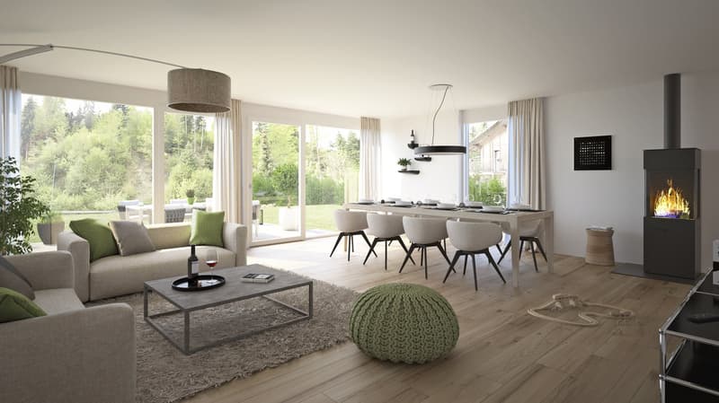 Spacious open-plan living and dining area with large windows offering a scenic view of the surrounding forest. The room features a modern fireplace, a gray sofa, a coffee table, and a dining table with chairs. The decor has a neutral color palette with po