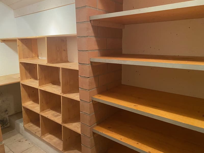 Wooden shelves in a room, brick wall, tiled floor, empty room.