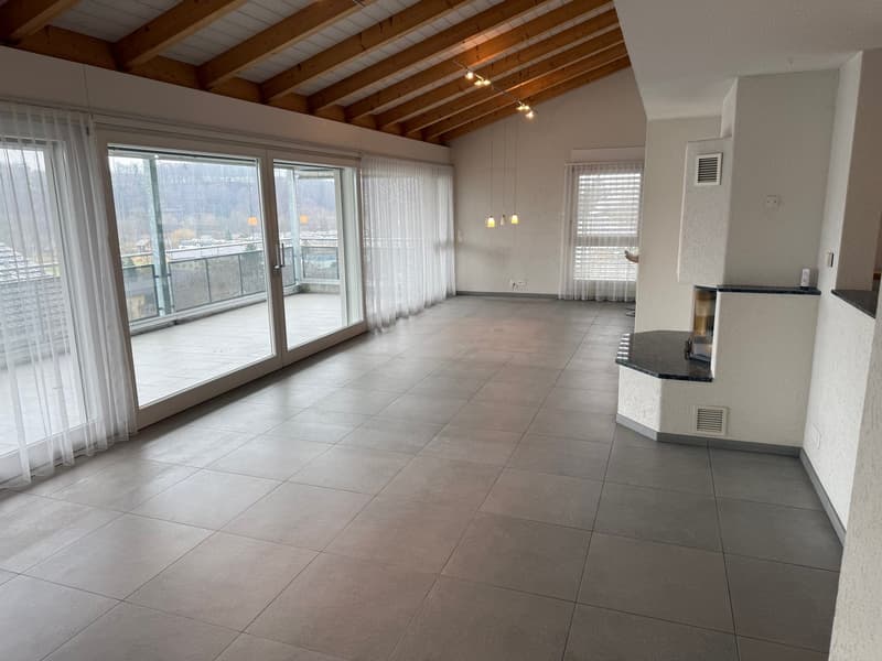 large room with balcony, large windows, tile floor, fireplace, wooden ceiling