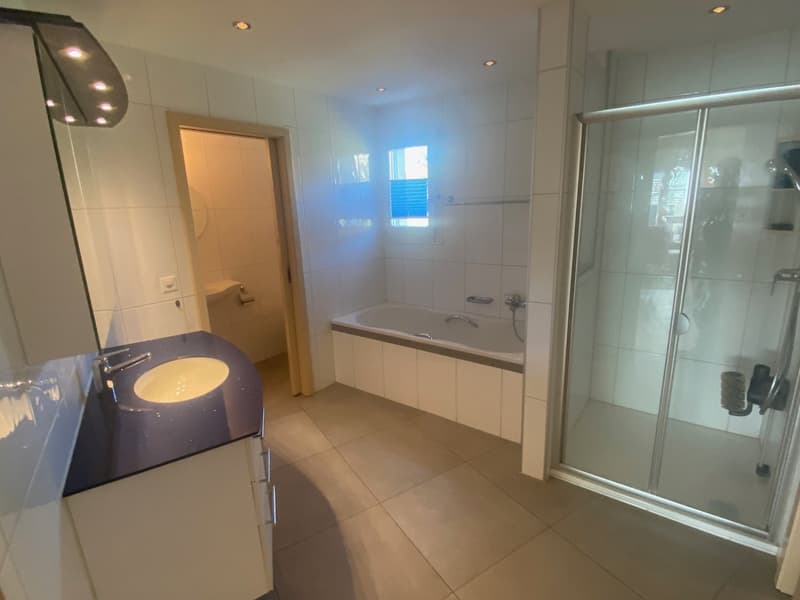 Modern bathroom with white tiles, a bathtub, a separate shower, a sink, and a toilet
